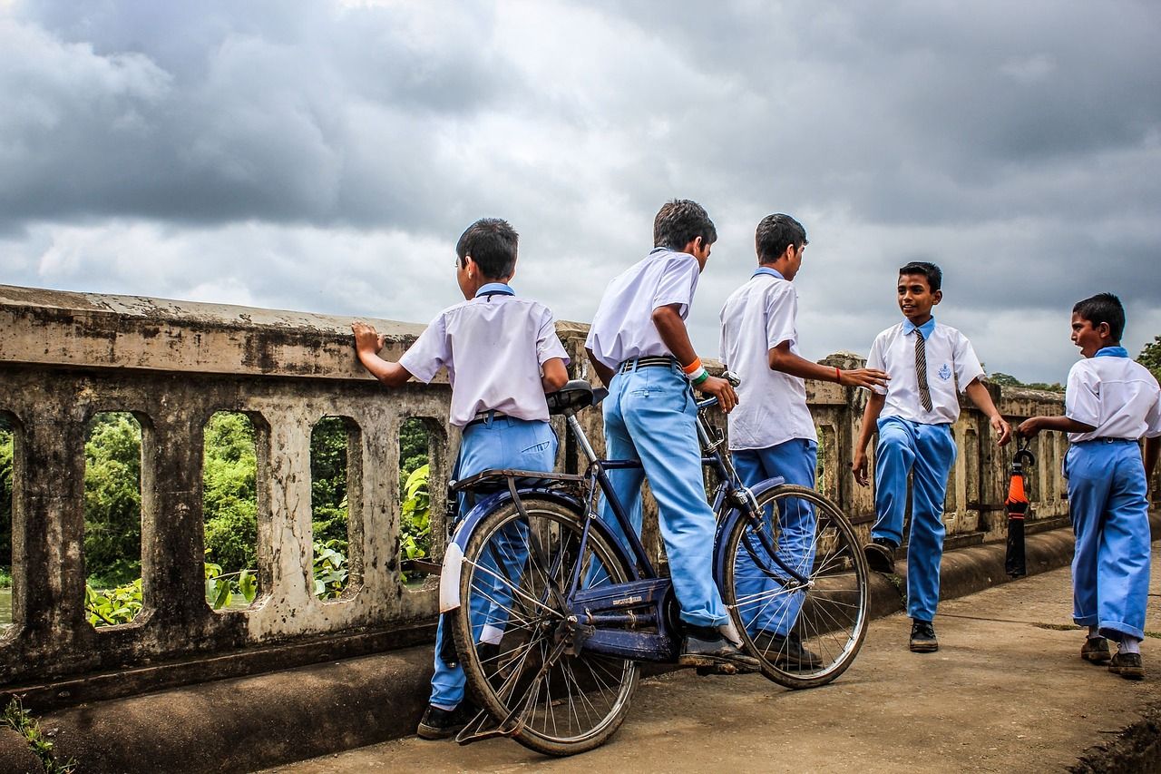 Students in school uniform crossing a bridge with their bicycles
